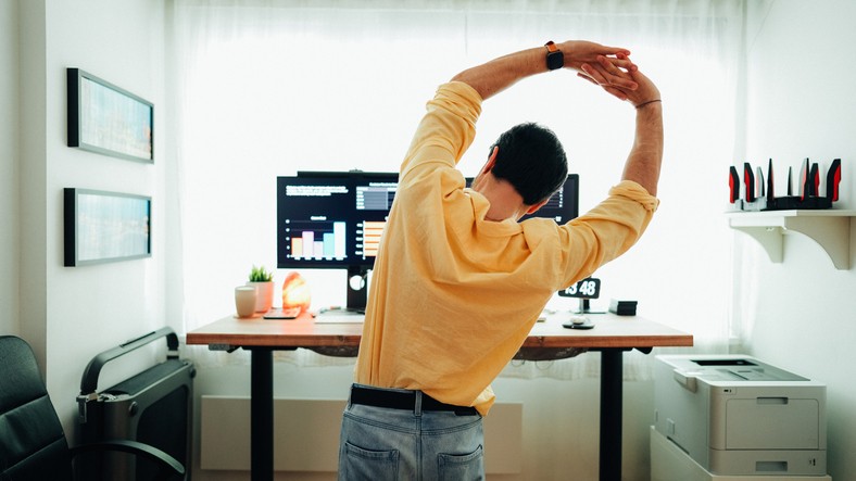 A man stretching after working for hours on a laptop