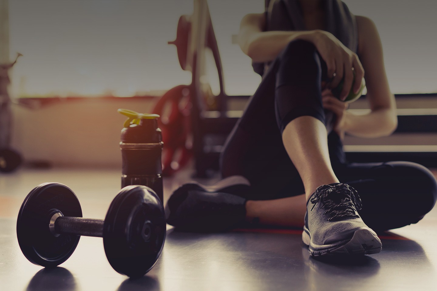 A Woman Sitting on the Floor & Holding a Dumbbell in South Denver 
