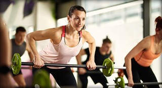 A group of women lifting barbells together in Wellbridge Athletic Club