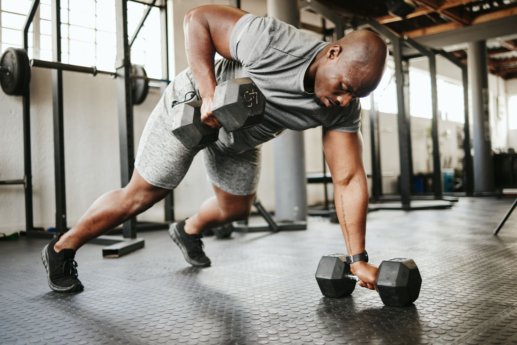 A man performs a push-up with two dumbbells, showcasing effective exercises for injury recovery in South Denver