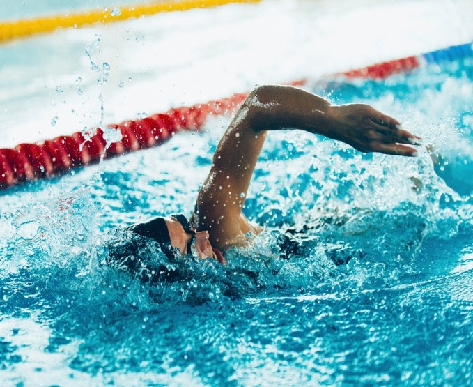 A swimmer splashes into a South Denver pool, highlighting the health benefits of swimming